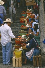 MEXICO, Market Scene, Girls selling fruit and vegetables on stone steps of market.