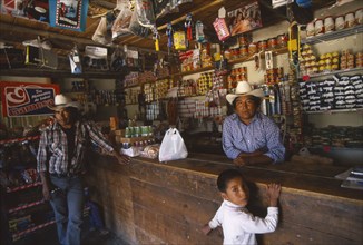 MEXICO, Chihuahua, Cusarare, Tarahumara Indian shopkeeper and customers at wooden counter inside
