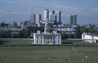 ENGLAND, London, Greenwich. View over lawn toward Queens House with the Canary Wharf skyline beyond