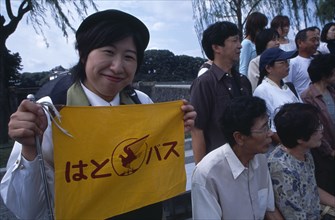 JAPAN, Honshu, Tokyo, Tour guide holding sign with tour group at the Imperial Palace