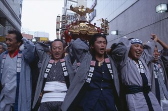 JAPAN, Honshu, Tokyo, Shinjuku. Men carrying Mikoshi throught the street during a festival