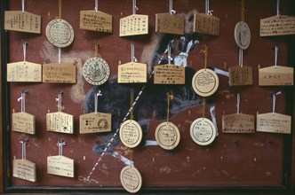 JAPAN, Honshu, Kyoto, Sanjusangen do Temple. Ema wooden votive tablets hanging from hooks on a wall