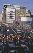 JAPAN, Honshu, Tokyo, Shinjuku. Crowded pedestrian crossing on busy city road with queues of