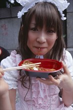 JAPAN, Honshu, Tokyo, Harajuku District. Portrait of young teenage girl eating noodles