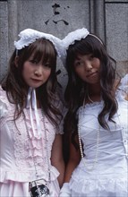 JAPAN, Honshu, Tokyo, Harajuku District. Portrait of two young teenage girls wearing pink and white