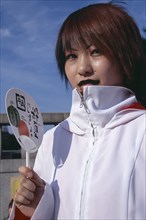 JAPAN, Honshu, Tokyo, Harajuku District. Portrait of a teenage girl wearing a white jacket holding