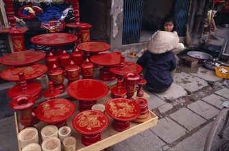 VIETNAM, North, Hanoi, Red lacquered dishes and pots displayed on pavement  with two women sitting