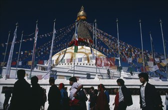 NEPAL, Bodhanath, "Pilgrims circling clockwise around Bodhanath Stupa draped with prayer flags