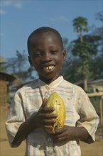GHANA, West, Children, Portrait of child holding cocoa pod.