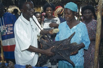 GHANA, West, Markets, "Man purchasing dried grasscutter, a type of large rodent, from woman on