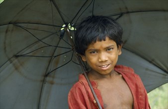 NEPAL, Terai Region, Children, Portrait of schoolboy with an umbrella.
