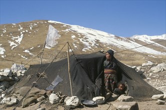 NEPAL, Mustang, Tibetan nomad woman and child looking out of tent made of yak wool on winter