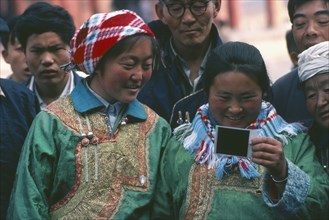 CHINA, Beijing, Tibetan women looking at polaroid pictures.