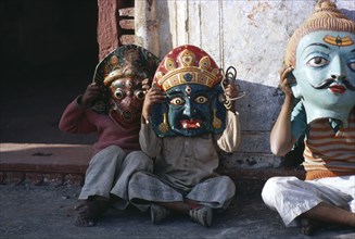 INDIA, Festival, Small children sitting in street wearing huge masks.