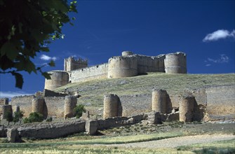 SPAIN, Castilla-Leon, Soria, Ruined castle and fortified walls on hillside.