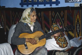 UKRAINE, Carpathian Mountains, Hutsul woman playing a guitar.
