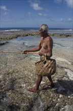 PACIFIC ISLANDS, Polynesia, Cook Islands, Atiu.  Lagoon fisherman with bamboo rod and woven basket.