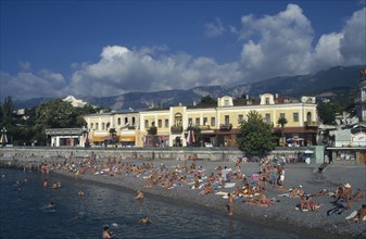UKRAINE, Crimea, Yalta, People sunbathing on narrow beach or swimming with promenade and waterside