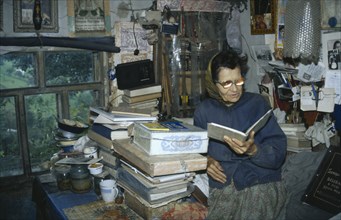 UKRAINE, Carpathian Mountains, Hutsul woman writer reading from open book in domestic interior.