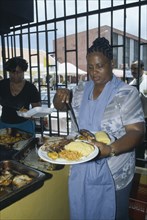 WEST INDIES, Dutch Antilles, Curacao, Female cook serving meal.