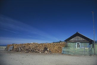 RUSSIA, Siberia, Lake Baikal, Buryat house with large stack of firewood at side.
