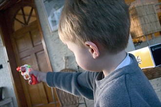 USA, Minnesota, St Paul, Boy aged 4 aiming colorful toy cap gun.