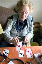 USA, Minnesota, Edina, Elderly woman playing Solitaire card game with large print cards.