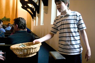 USA, Minnesota, St Paul, Young boy passing the offering basket at Unity Church Unitarian.