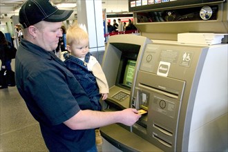 USA, Minnesota, Minneapolis, Father with baby son withdrawing cash at the ATM machine in the