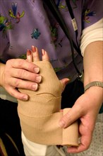 USA, Minnesota, Plymouth, Emergency room nurse wrapping temporary elastic bandage on broken wrist.