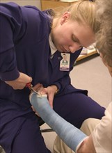 USA, Minnesota, Plymouth, Clinic nurse making adjustments to cast with cutter for elderly patient
