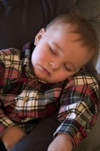 USA, Minnesota, Plymouth, 1 year old grandson sound asleep at the family Christmas party.