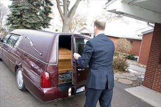 USA, Minnesota, St Paul, Funeral director closing back door of hearse on coffin.