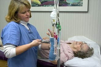 USA, Minnesota, Plymouth, Clinic nurse removing cast from broken wrist of 90 year old patient