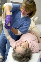 USA, Minnesota, Plymouth, Clinic nurse recasting broken wrist of 90 year old patient