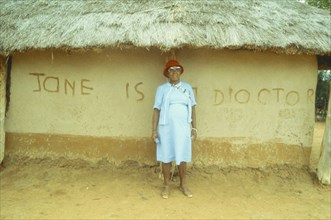 BOTSWANA, People, Traditional healer standing outside thatched hut with ‘Jane is a doctor’ written