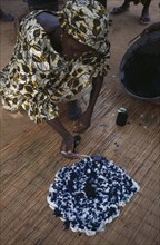 GAMBIA, Work, Woman using indigo coloured dye to tie dye fabric.