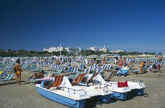 ITALY, Emilia-Romagna, Rimini, Busy beach scene with rows of striped sun loungers and pedalos in