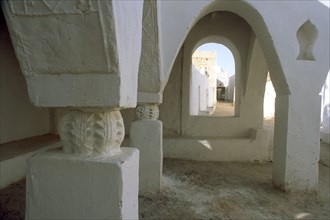 LIBYA, Ghadames, Tarasan Square.  Arched window in wall of passageway framing white painted town