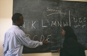 SOMALILAND, Hargeisa, Teacher and pupil writing letters on blackboard at school for returnees in