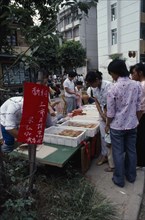 CHINA, Guangxi Zhuang, Nanning, Young women at street stall selling moon cakes for Moon Festival.