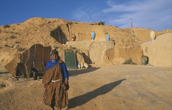 TUNISIA, Zaraova, Portrait of a Berber woman standing outside her home which is dug out of a