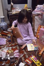 FESTIVALS, Christmas, Presents, Five year old girl sitting on the floor opening her Christmas