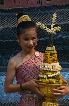 LAOS, Luang Prabang, Young girl in traditional dress with flower offering at New Year celebrations.