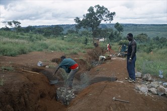 TANZANIA, West, Great Lakes Region, Refugees making gambions to prevent water erosion.  Base of