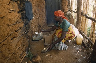 TANZANIA, West, Great Lakes Region, Refugee woman cooking on wood saving clay stove inside hut with