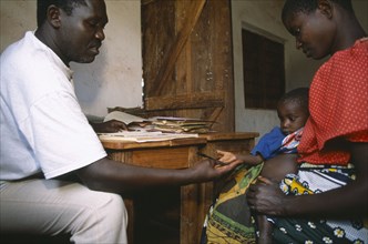 TANZANIA, West, Great Lakes Region, Refugee camp health centre.  Male staff with woman and child.