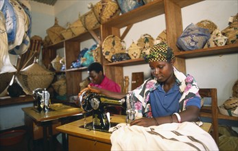 TANZANIA, West, Great Lakes Region, Women using sewing machines in dressmaking workshop in refugee