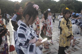 JAPAN, Honshu, Tokyo, Harajuku. A member of Kyoto Rokumeikan troupe checks her mobile / cell phone