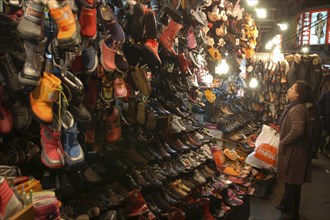 KOREA, Seoul, Namdaemun Market. Woman shopping for shoes on a cold December night